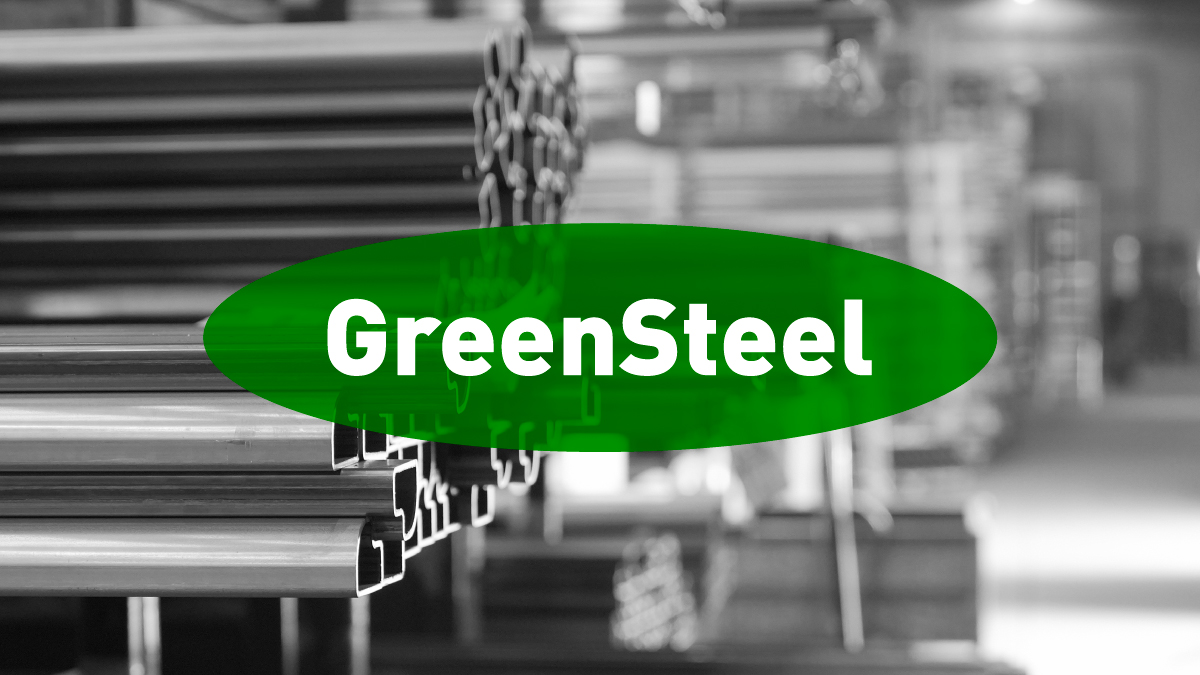 Stacks of steel beams in a warehouse, shown in black and white, with a green oval overlay in the center displaying the word "GreenSteel" in bold white letters.