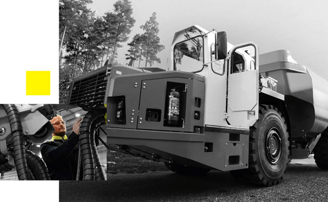 A large industrial dump truck is parked on a road near trees. An inset shows a person wearing glasses and a safety jacket inspecting or repairing the front of the vehicle. The image is mostly in grayscale with yellow accents.